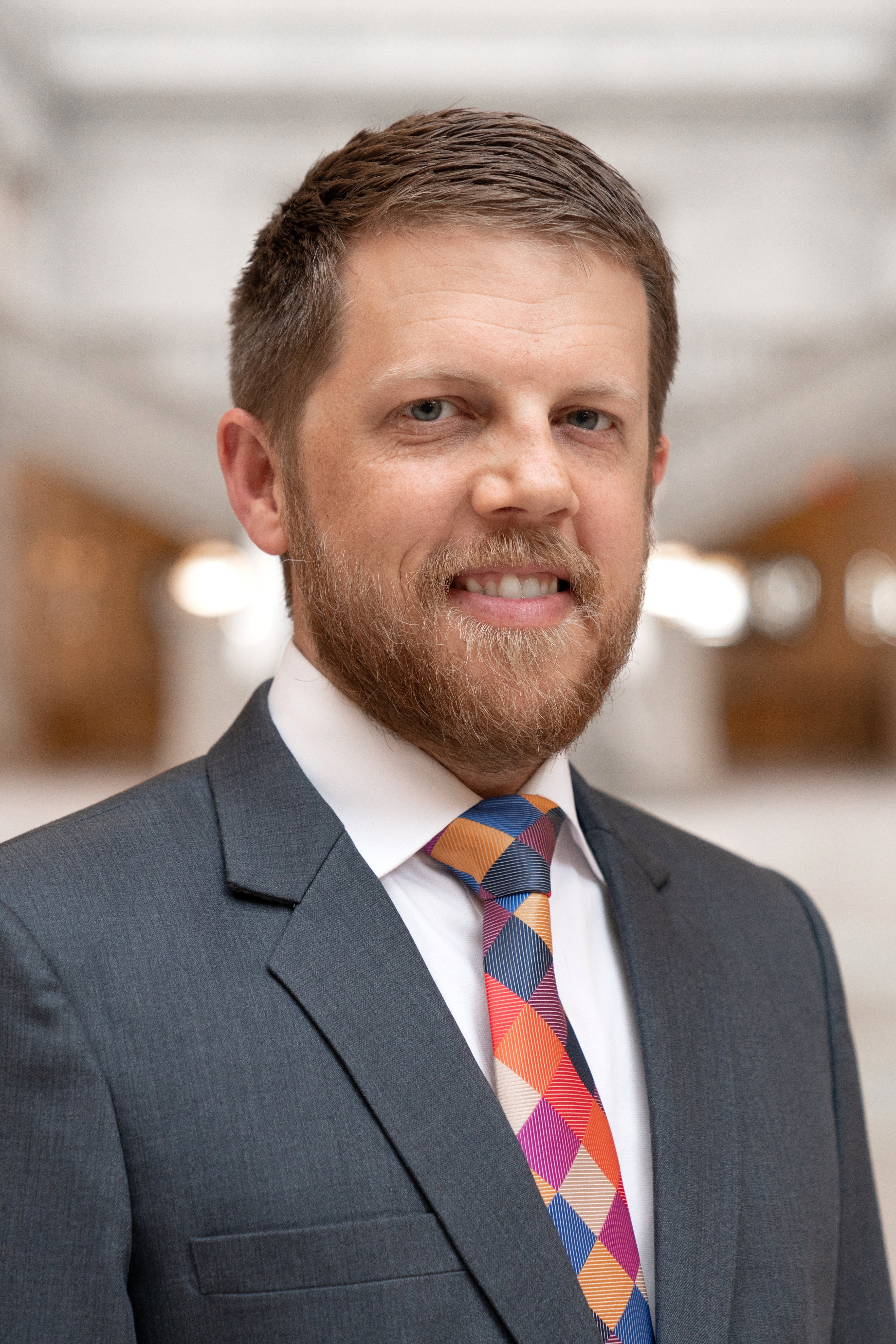 Connor Boyack wearing a gray suit with a colorful tie in an indoor setting